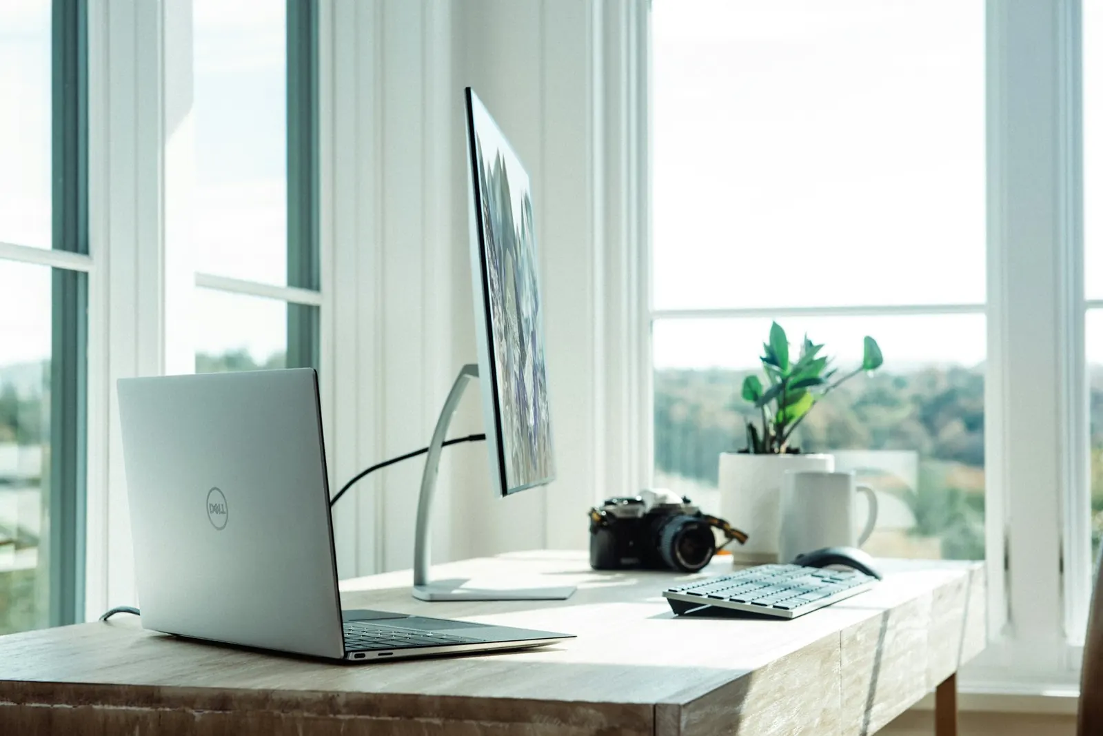 Home office desk with a monitor beside a bright window