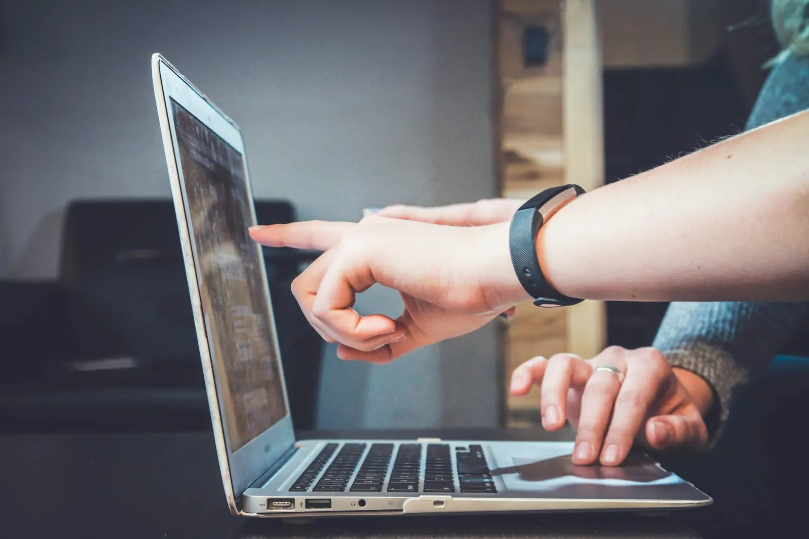 Hands pointing at a laptop screen during a discussion