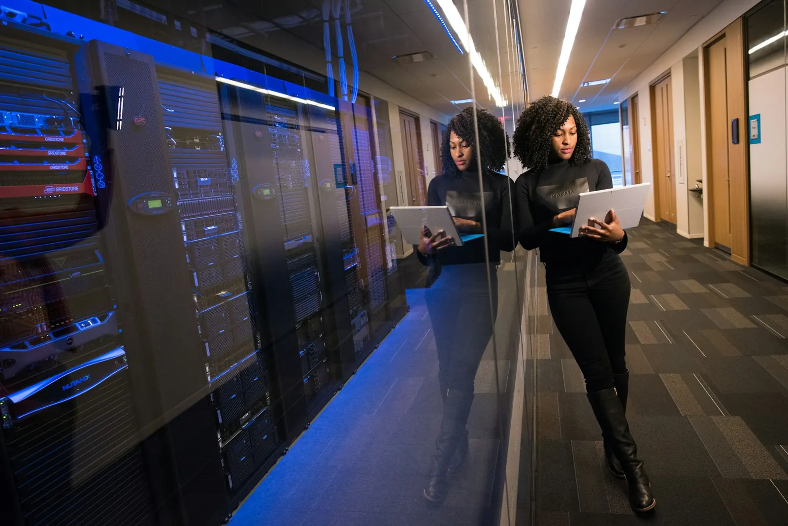 Person walking a server-room aisle while using a tablet