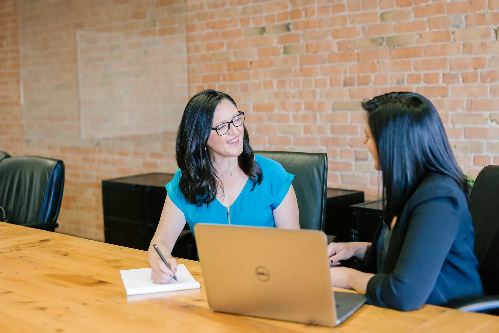 Two women talking through a problem with laptops open