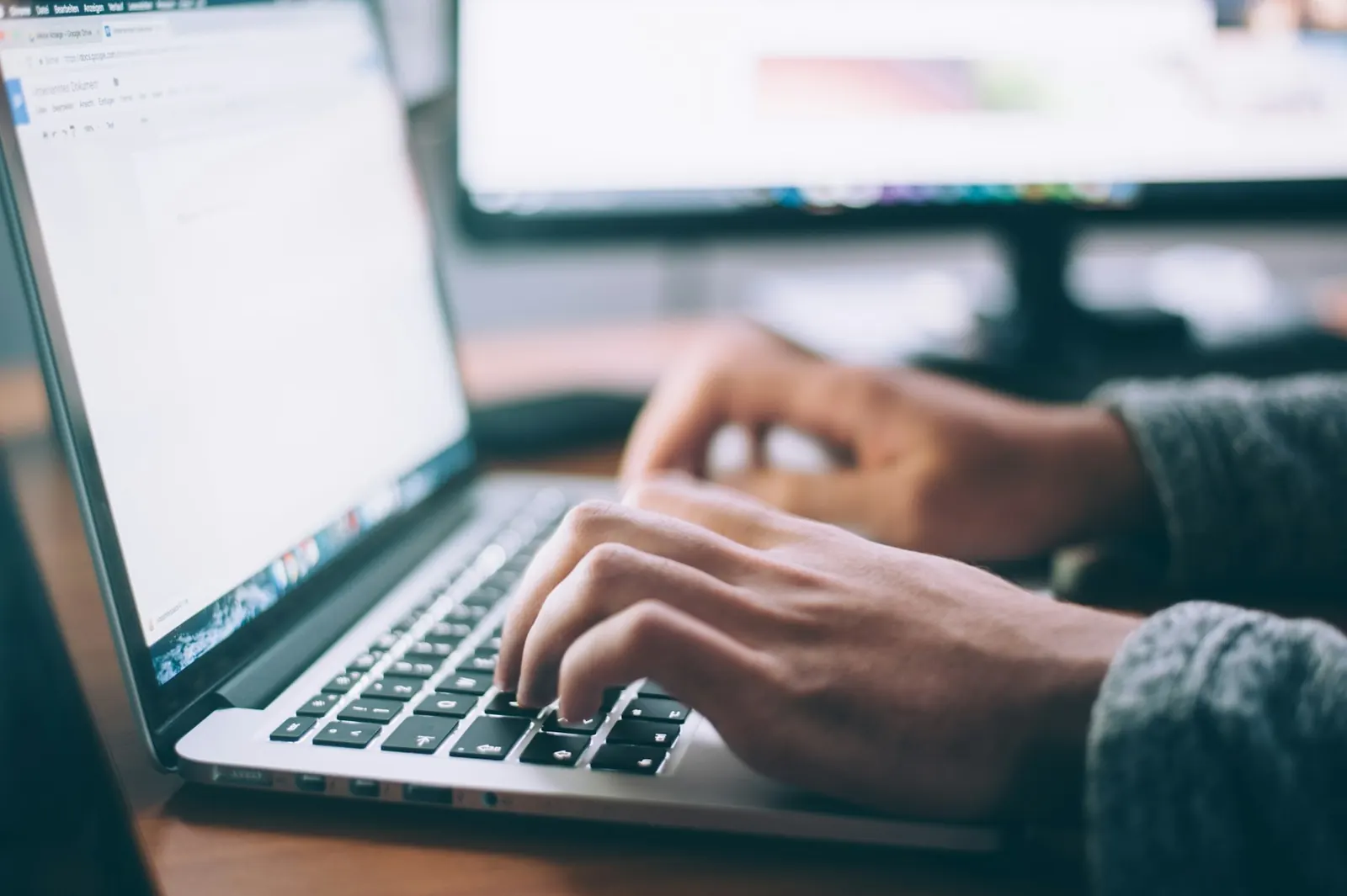 Hands typing on a laptop in a bright room